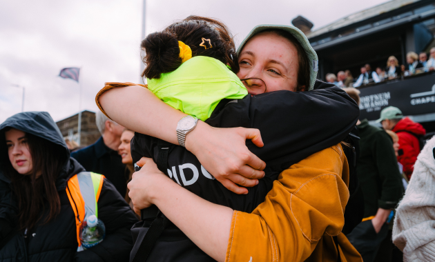 Two people hugging in celebration at the Boat Race - Dig & Dig